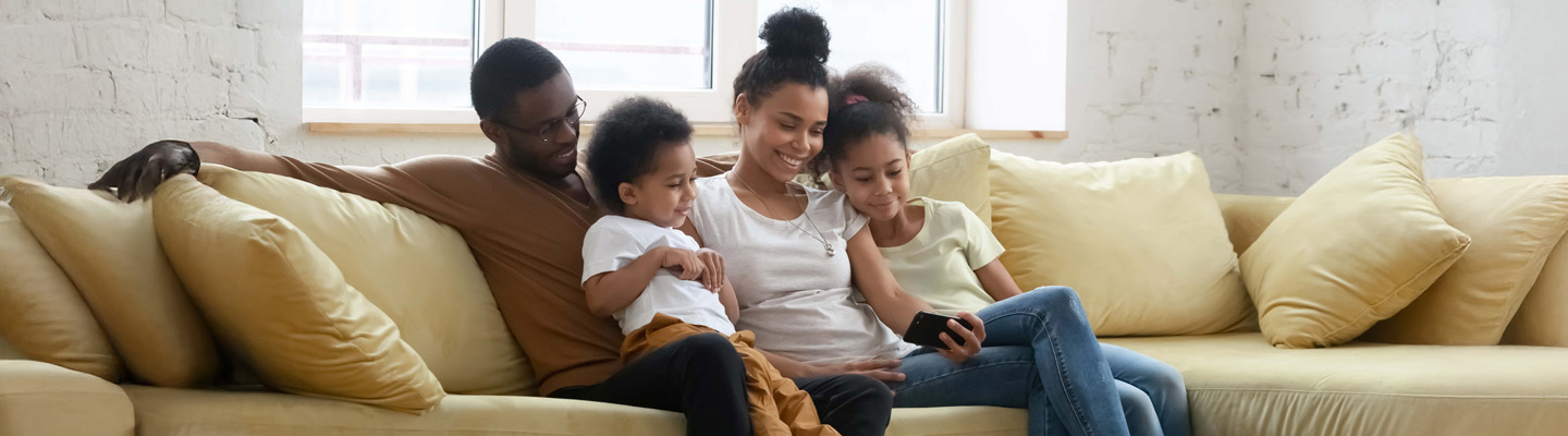 Happy biracial family with kids using cellphone together