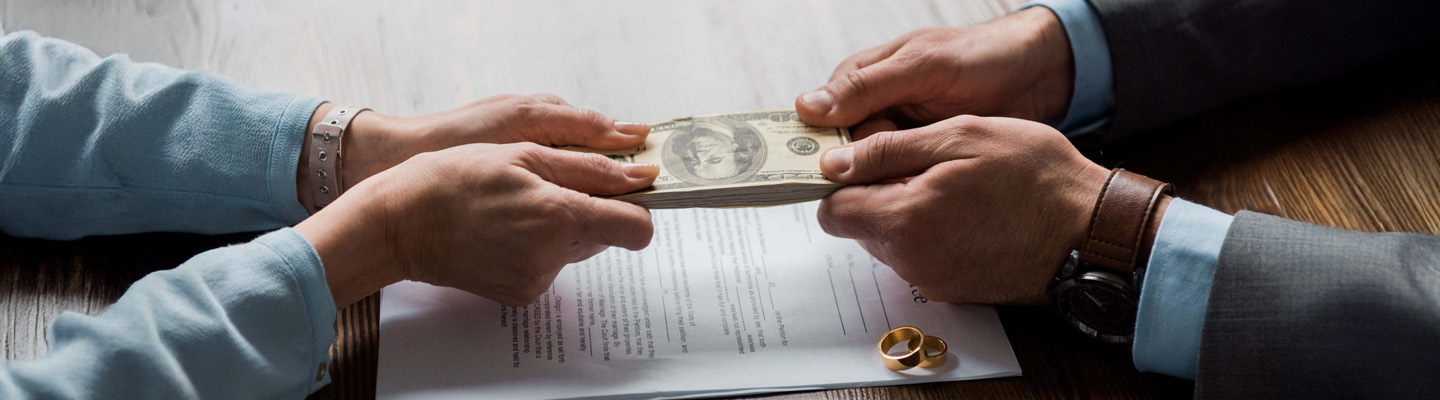 partial view of lawyer and client holding dollar banknotes above divorce decree with wedding rings