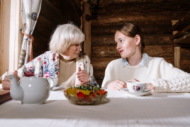 elderly woman sitting at table with teen