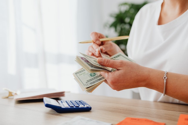 woman counting bills with calculator